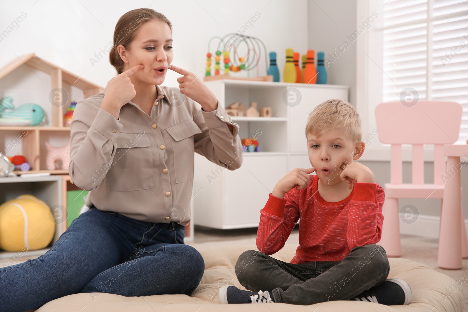 Photo of Speech therapist working with little boy in office