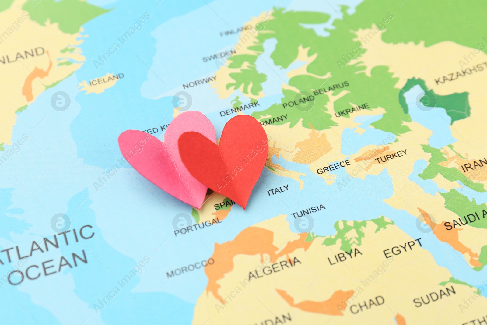 Photo of Honeymoon concept. Two red paper hearts on world map, closeup