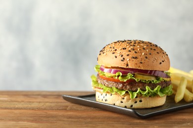 Photo of Burger with delicious patty and french fries on wooden table, space for text