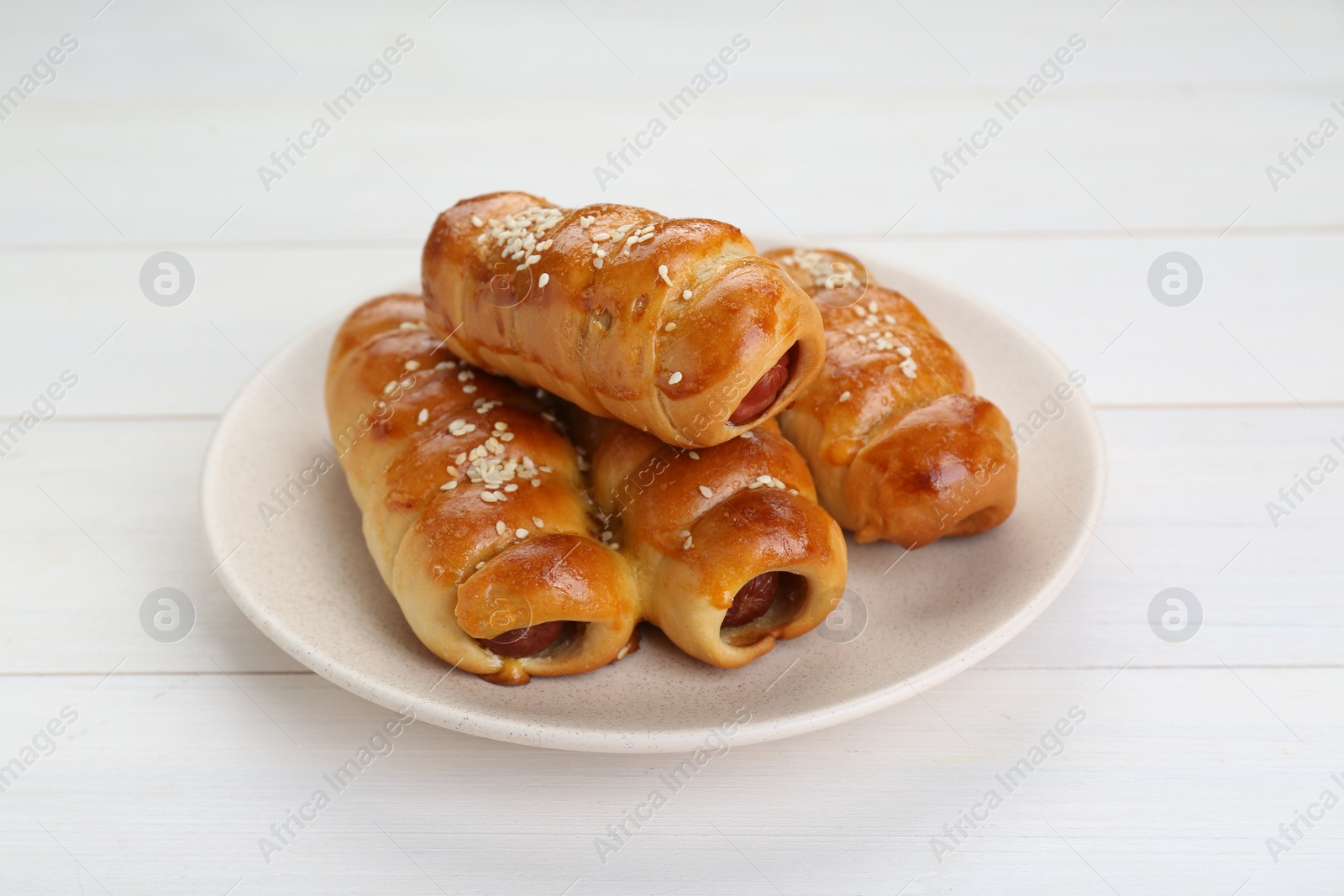 Photo of Delicious sausage rolls on white wooden table