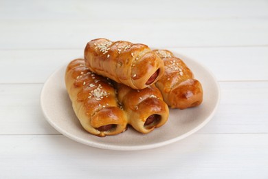 Photo of Delicious sausage rolls on white wooden table