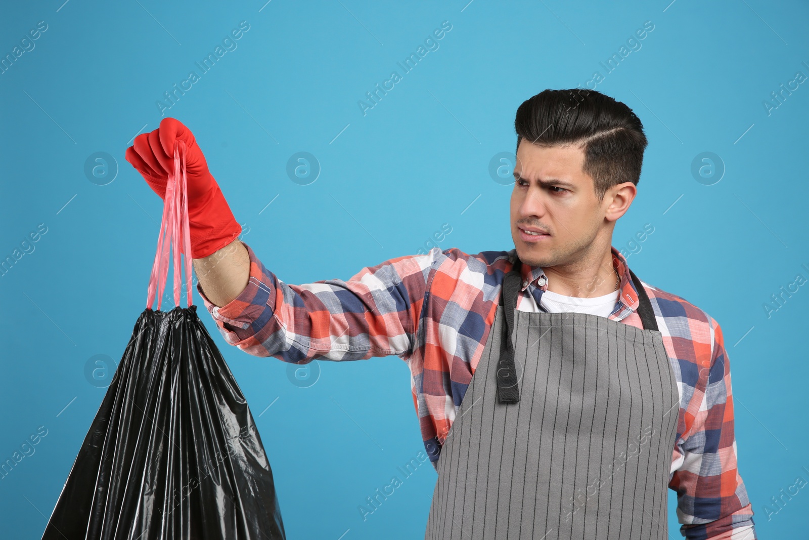 Photo of Man holding full garbage bag on light blue background