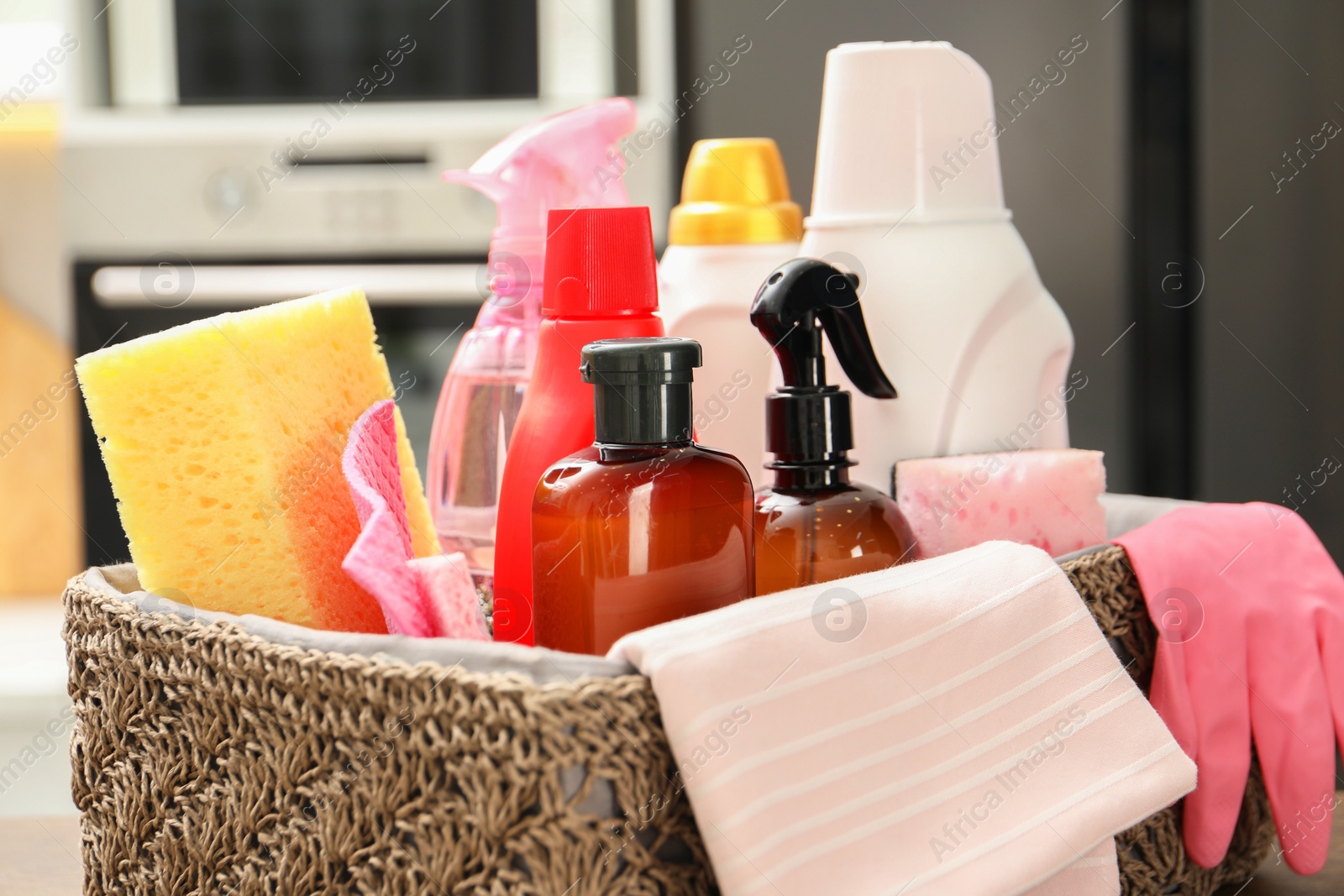 Photo of Different cleaning supplies in basket on table, closeup