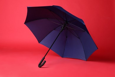 Photo of Stylish open blue umbrella on red background