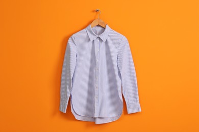 Photo of Hanger with striped shirt on orange wall