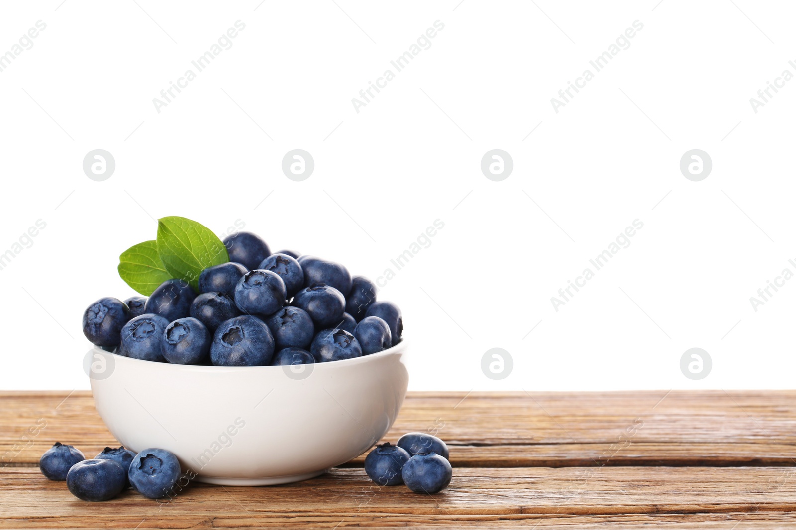 Photo of Bowl with tasty fresh blueberries on wooden table against white background