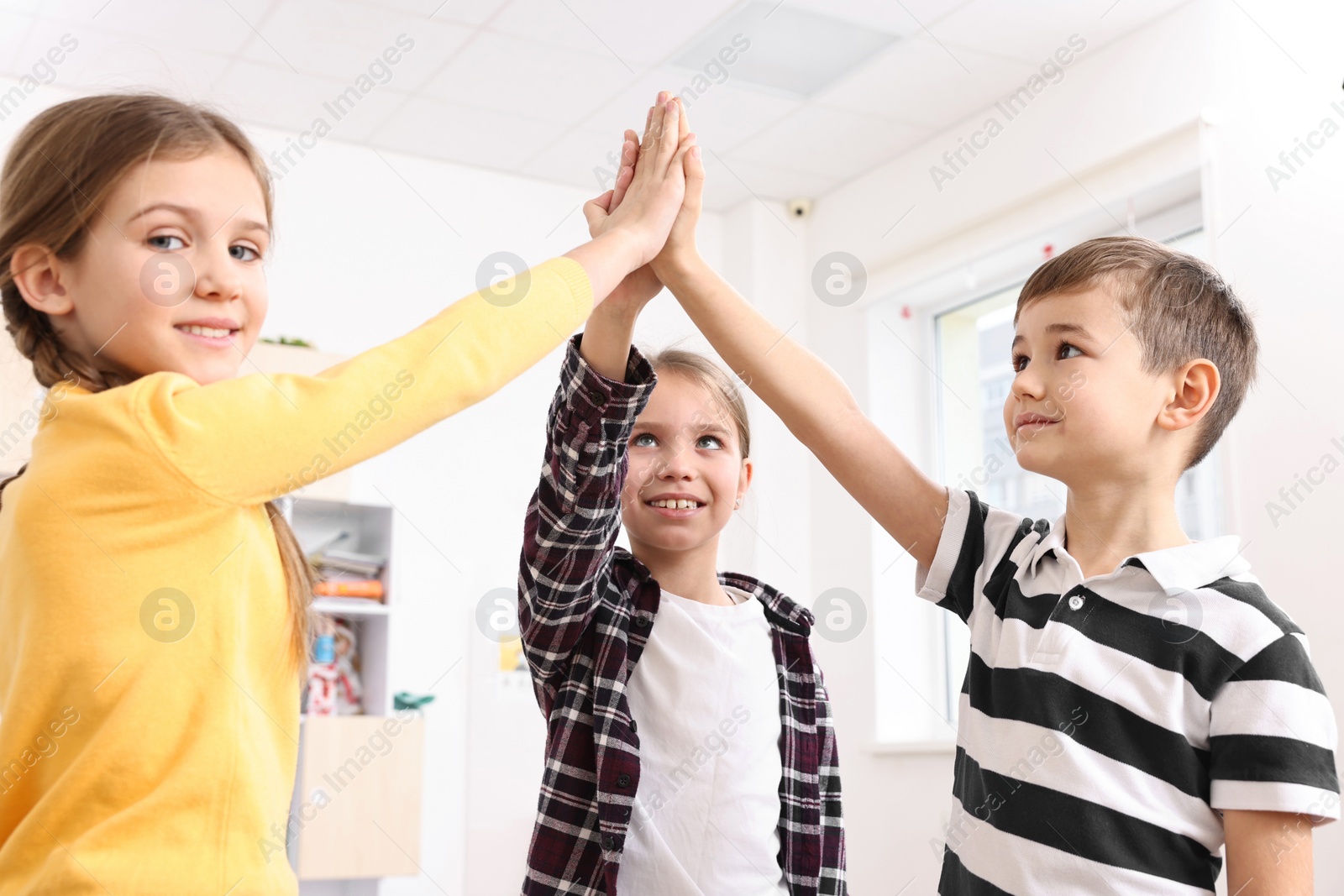 Photo of Happy children giving high five at school