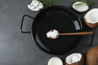 Photo of Flat lay composition with frying pan and organic coconut cooking oil on grey table, space for text