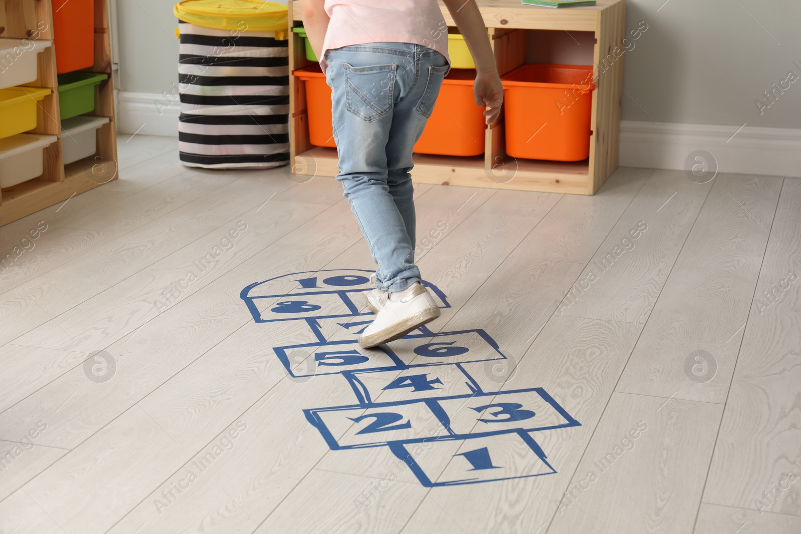 Photo of Little girl playing hopscotch at home, closeup