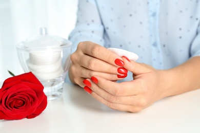 Woman removing nail polish at white table, closeup