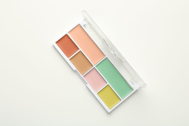 Photo of Colorful correcting concealer palette on white background, top view