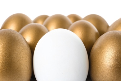 Photo of Golden eggs with different one on white background