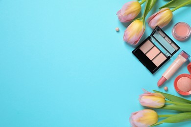 Flat lay composition with different makeup products and beautiful tulips on light blue background. Space for text