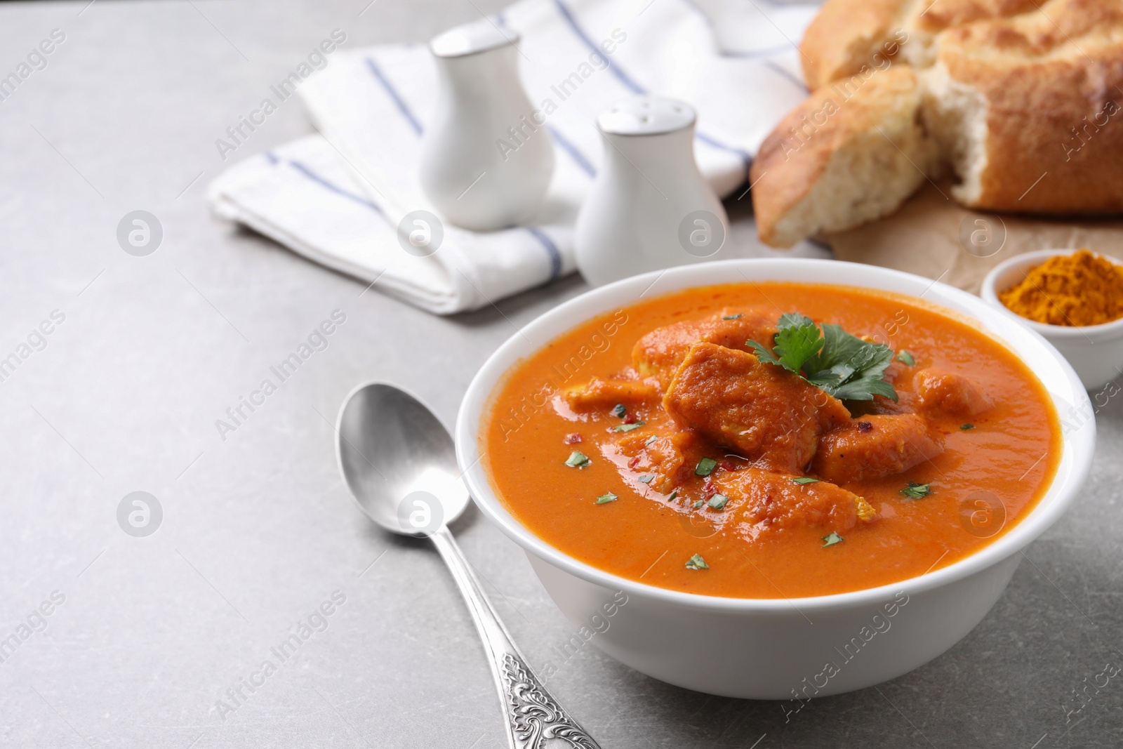 Photo of Bowl of delicious chicken curry on light grey table, space for text