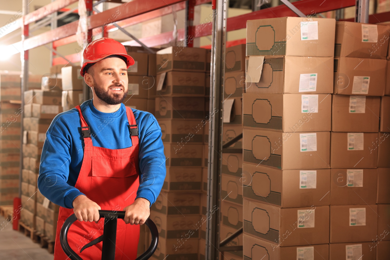 Image of Worker with pallet jack at warehouse. Logistics center