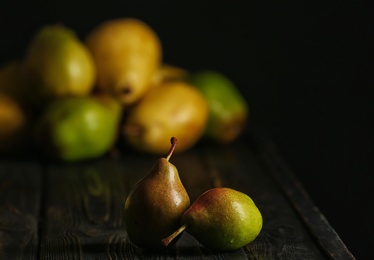 Fresh ripe pears on dark table against blurred background