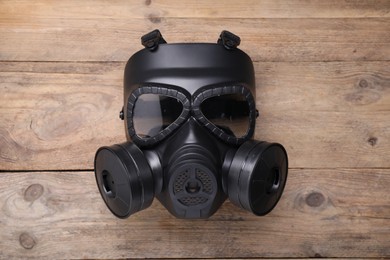 Photo of One gas mask on wooden background, top view