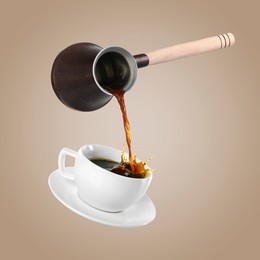 Pouring freshly brewed aromatic coffee from turkish pot into cup. Objects in air on dark beige background