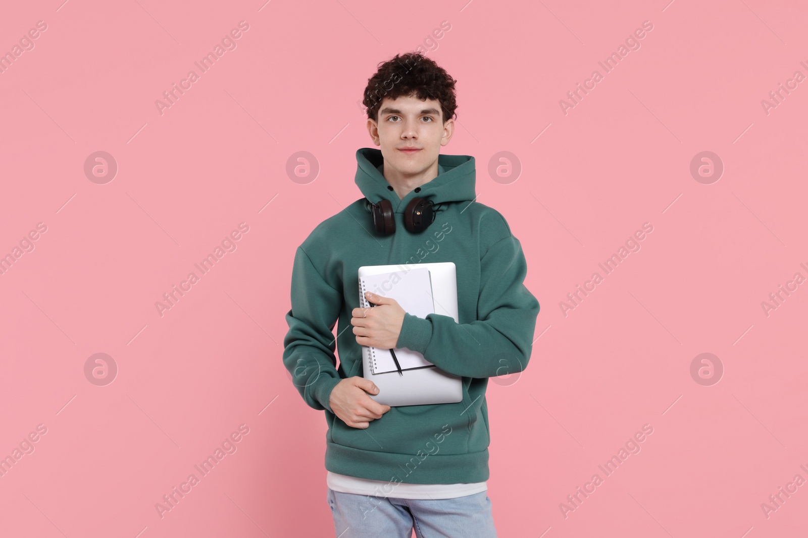Photo of Portrait of student with laptop, notebook and headphones on pink background