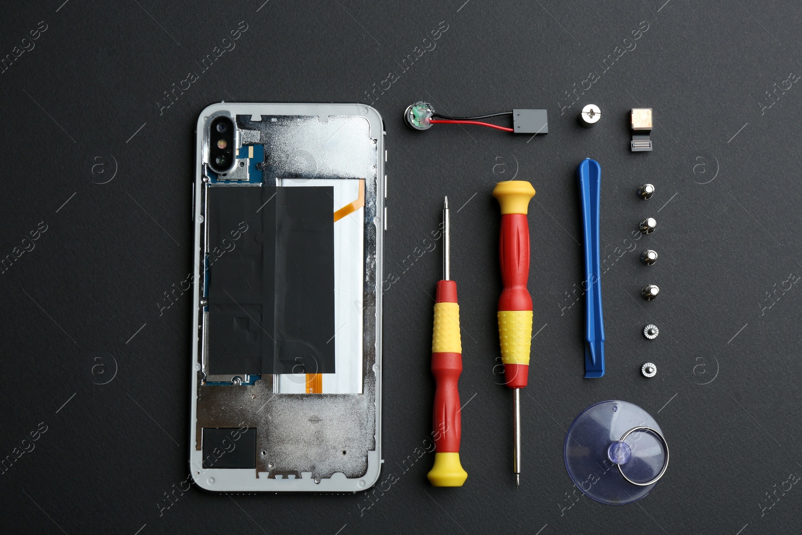 Photo of Disassembled mobile phone and repair tools on black background, flat lay