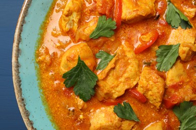 Photo of Delicious chicken curry on blue table, top view