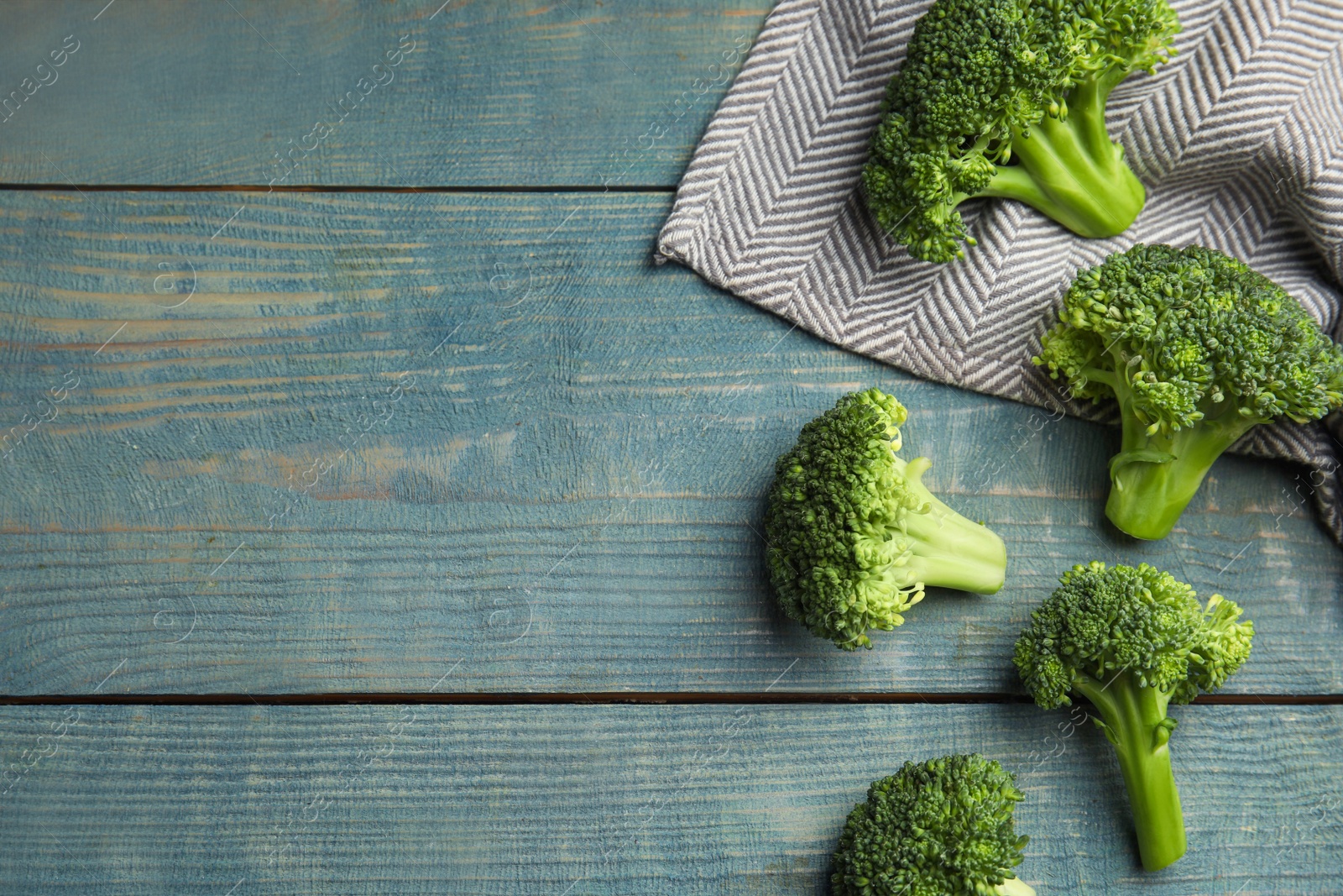 Photo of Fresh green broccoli on blue wooden table, flat lay. Space for text