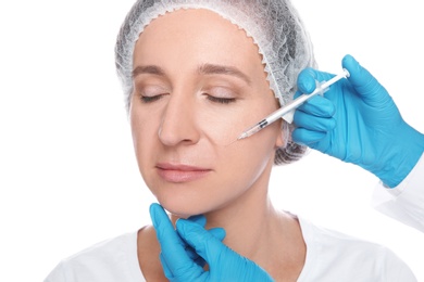 Mature woman getting facial injection on white background. Cosmetic surgery concept