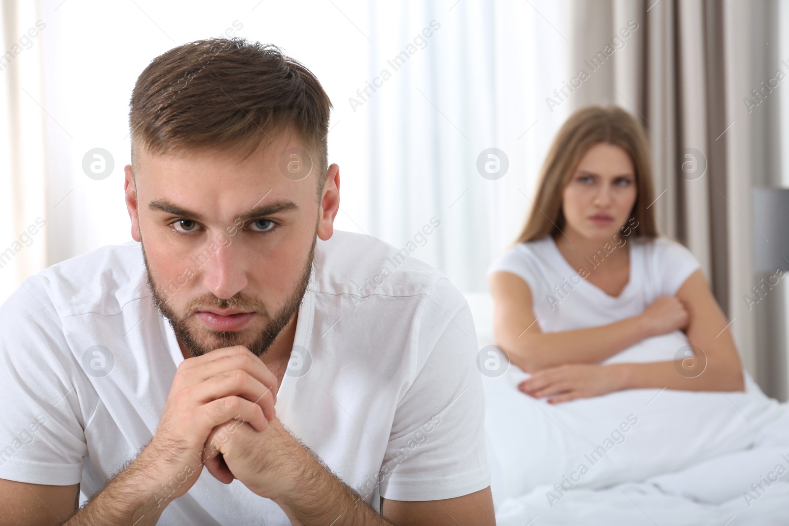 Photo of Young couple with relationship problems ignoring each other in bedroom