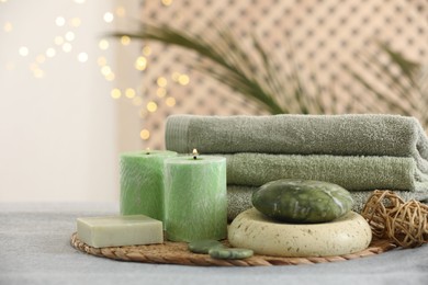 Photo of Spa composition. Burning candles, stones, soap and towels on soft grey surface