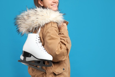 Photo of Happy woman with ice skates on light blue background, closeup. Space for text
