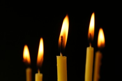 Burning church candles on black background, closeup