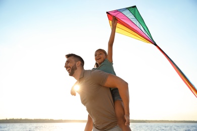 Photo of Happy father and his child playing with kite near sea. Spending time in nature