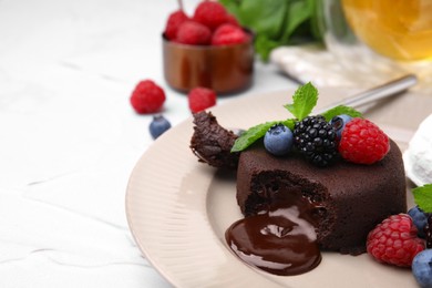 Delicious chocolate fondant served with fresh berries on white textured table, closeup. Space for text