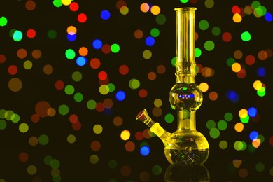 Glass bong against blurred lights, space for text. Smoking device