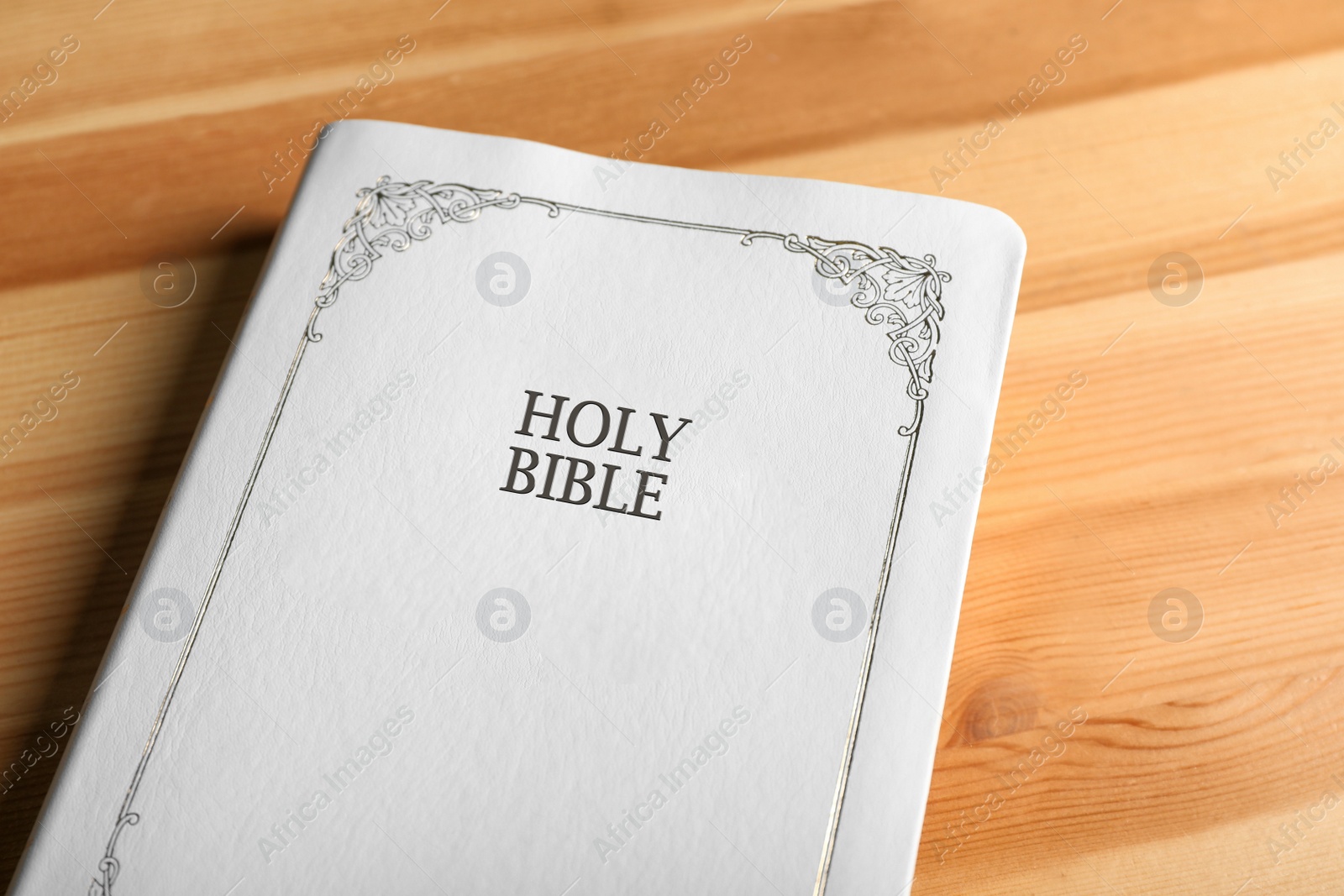 Photo of Bible with white cover on wooden table, closeup