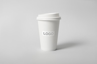 Takeaway paper coffee cup with logo on light grey background