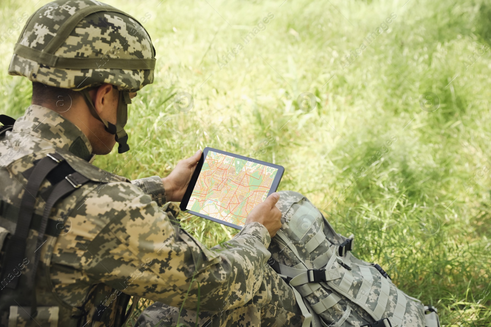 Photo of Soldier with backpack using tablet in forest