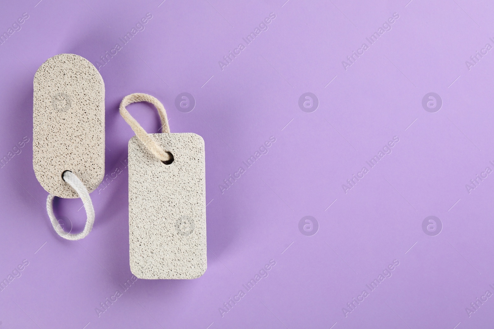 Photo of Pumice stones on violet background, flat lay. Space for text