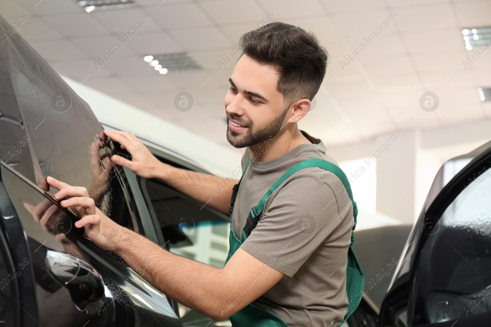 Photo of Worker tinting car window with foil in workshop