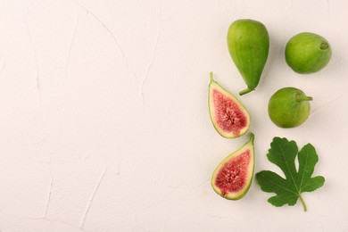 Cut and whole green figs with leaf on light table, flat lay. Space for text