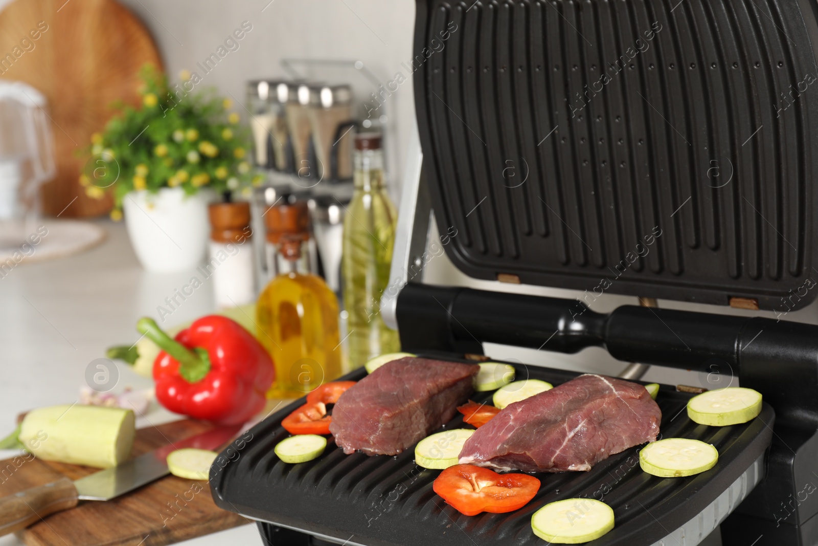 Photo of Electric grill and different products on white wooden table, closeup