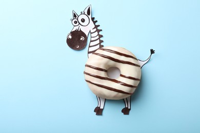 Photo of Funny zebra made with donut on light blue background, top view