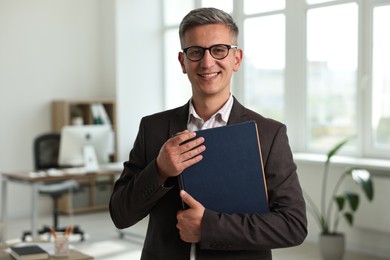 Portrait of happy man with notebooks in office