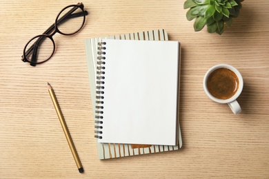 Photo of Flat lay composition with notebooks, coffee and glasses on wooden background