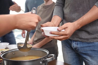 Photo of Volunteer serving food to poor people in charity centre, closeup