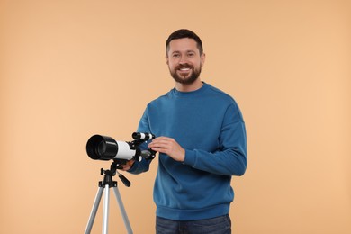 Photo of Smiling astronomer with telescope on beige background