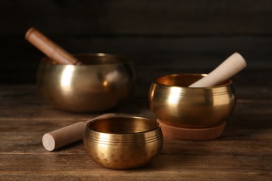 Golden singing bowls with mallets on wooden table