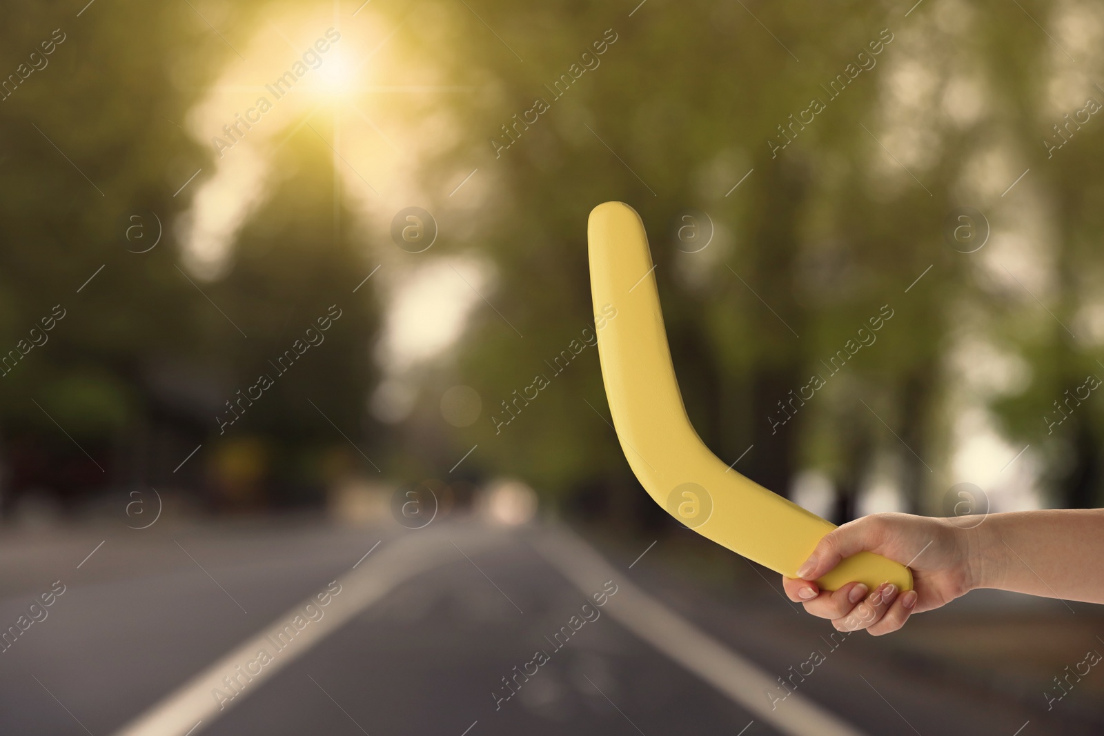 Image of Woman holding yellow boomerang outdoors, closeup. Space for text