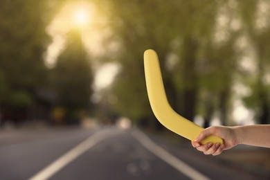 Image of Woman holding yellow boomerang outdoors, closeup. Space for text