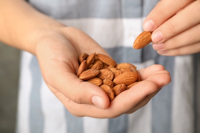 Photo of Woman holding organic almond nuts in hands, closeup